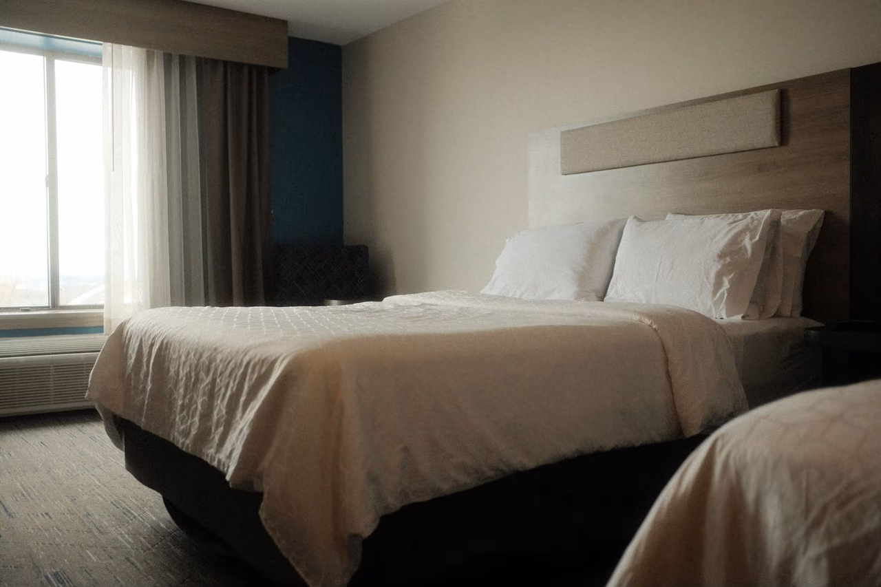 Neatly made bed with white linens and soft lighting in a quiet hotel room