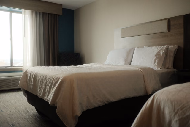 Neatly made bed with white linens and soft lighting in a quiet hotel room