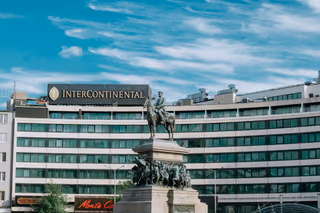 InterContinental hotel facade with its rooftop sign behind a bronze equestrian statue under a blue sky