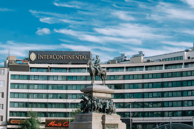 InterContinental hotel facade with its rooftop sign behind a bronze equestrian statue under a blue sky
