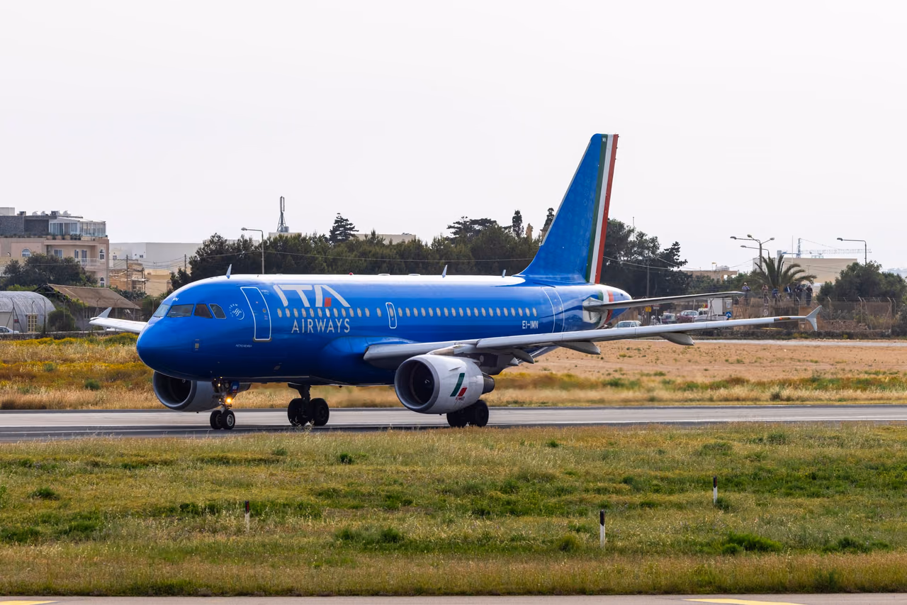 ITA Airways Airbus jet in bright blue livery with an Italian flag tail stripe on a runway