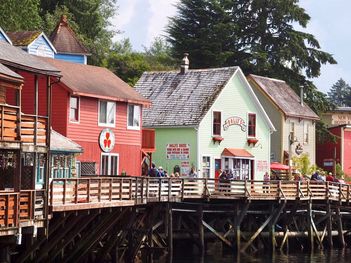 Colorful wooden houses along the Ketchikan, Alaska waterfront with people walking on a wooden dock