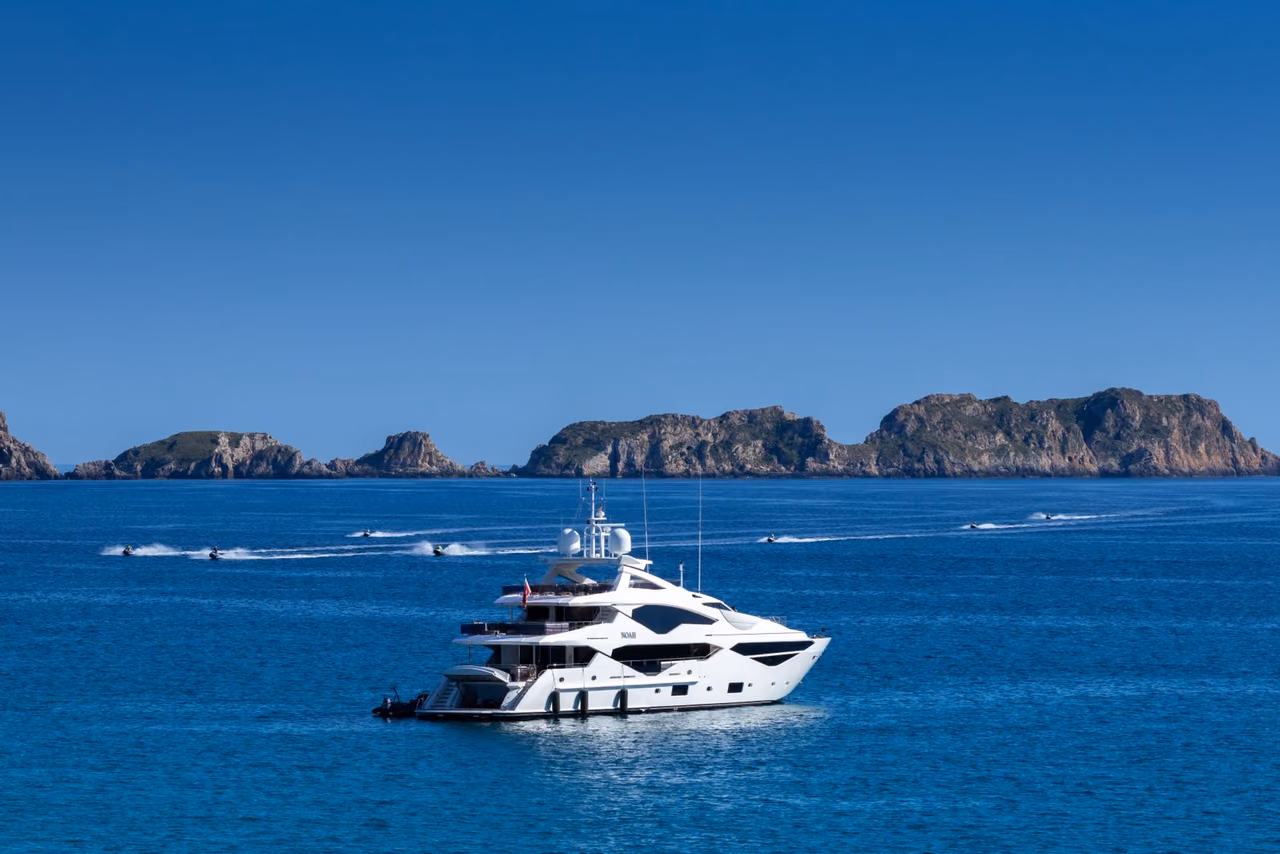 White luxury yacht on deep blue water with a rocky island chain behind it