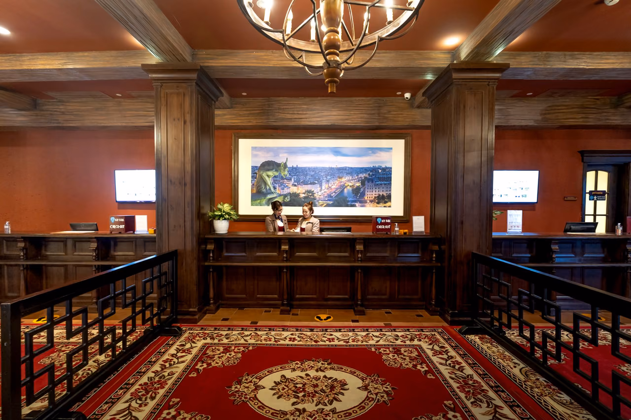 Hotel reception desk with wood paneling and patterned carpet in a quiet lobby