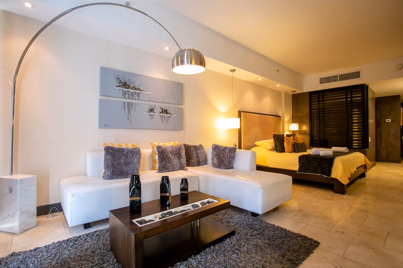 Hotel suite with a white sectional sofa, coffee table and a double bed