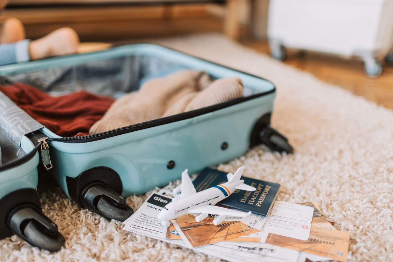 An open suitcase with a passport and travel tickets on top, ready for a trip