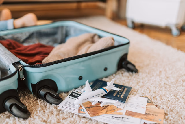 An open suitcase with a passport and travel tickets on top, ready for a trip
