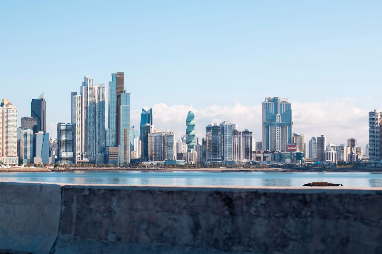 Panama City's waterfront skyline of tall glass towers under a clear blue sky