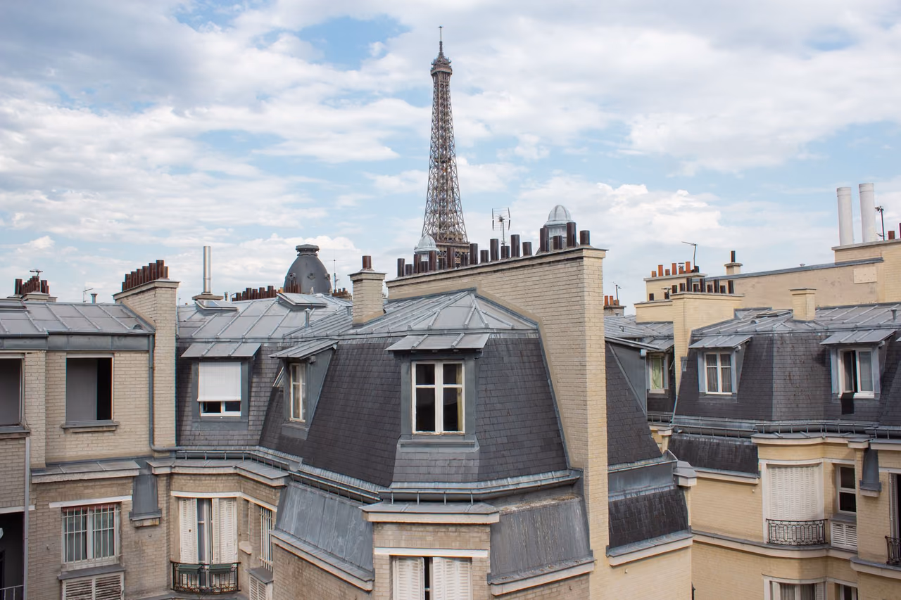 Parisian rooftops with the Eiffel Tower in the distance on a clear day