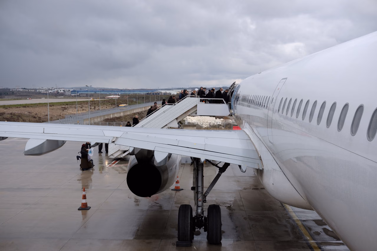 Passengers boarding a large airplane at an airport on an overcast day
