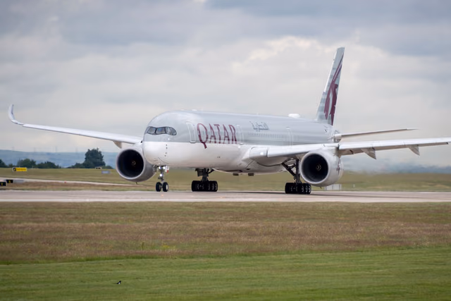 A Qatar Airways Airbus A350 on a runway under a cloudy sky, preparing for takeoff
