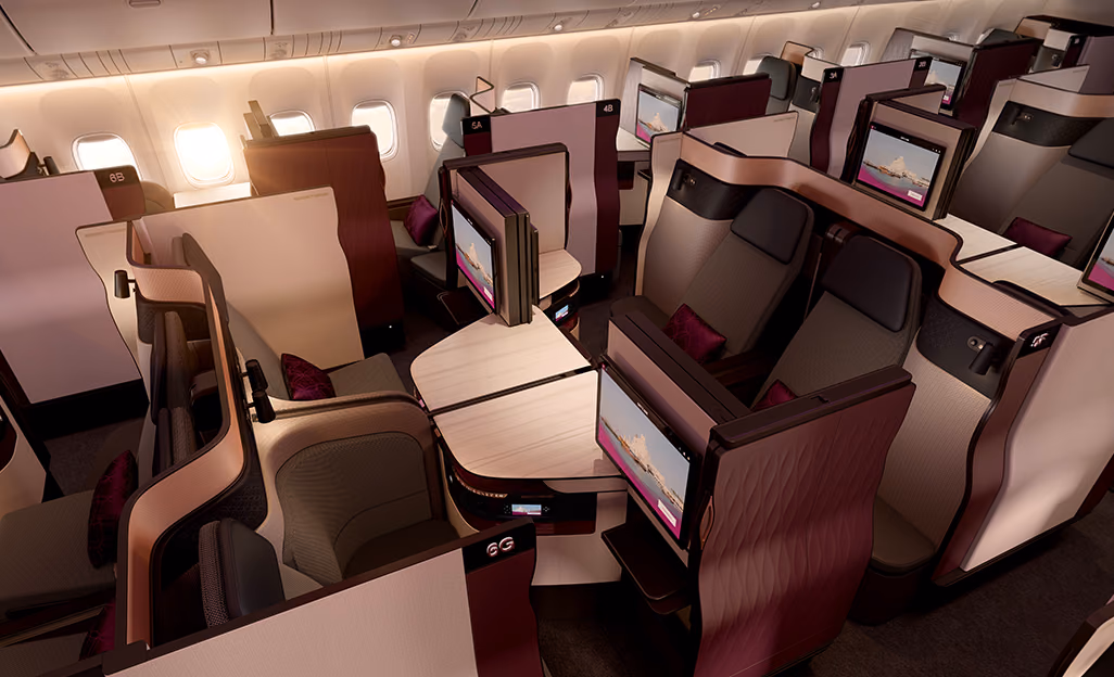 Rendering of a Qatar Airways Qsuite business class cabin, with four suites facing each other around joined center tables, privacy panels and seatback screens