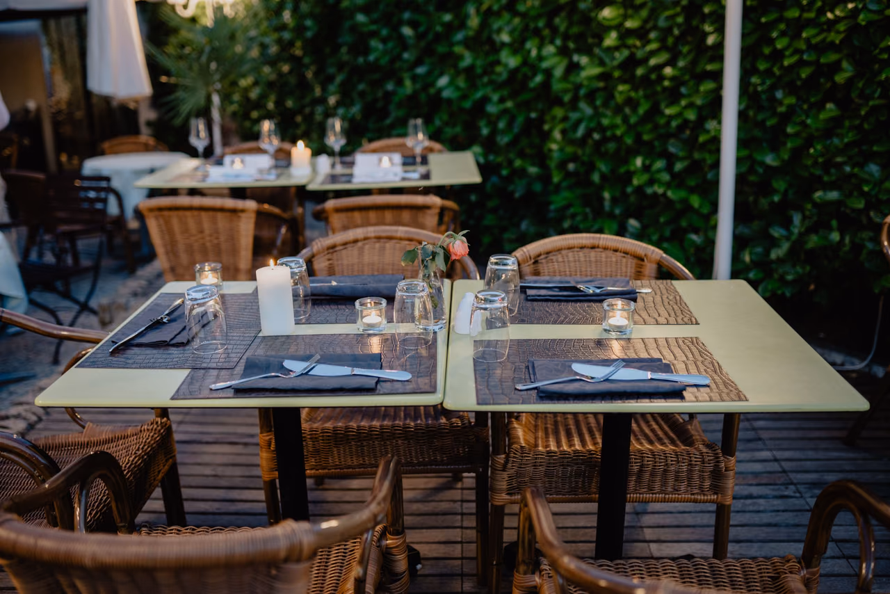 Candlelit tables with wicker chairs on a restaurant terrace