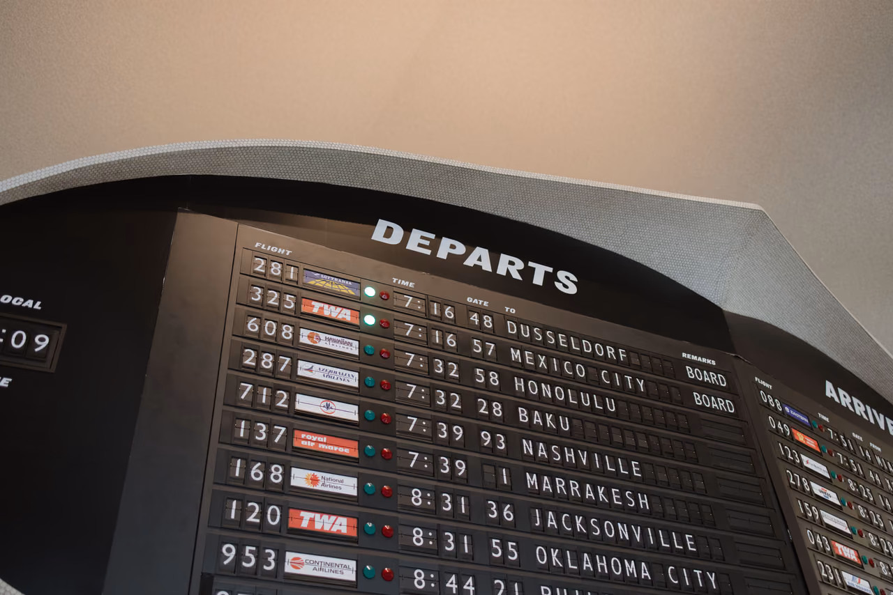 A retro split-flap airport departures board listing flight numbers, times and gates for cities including Honolulu, Nashville and Jacksonville