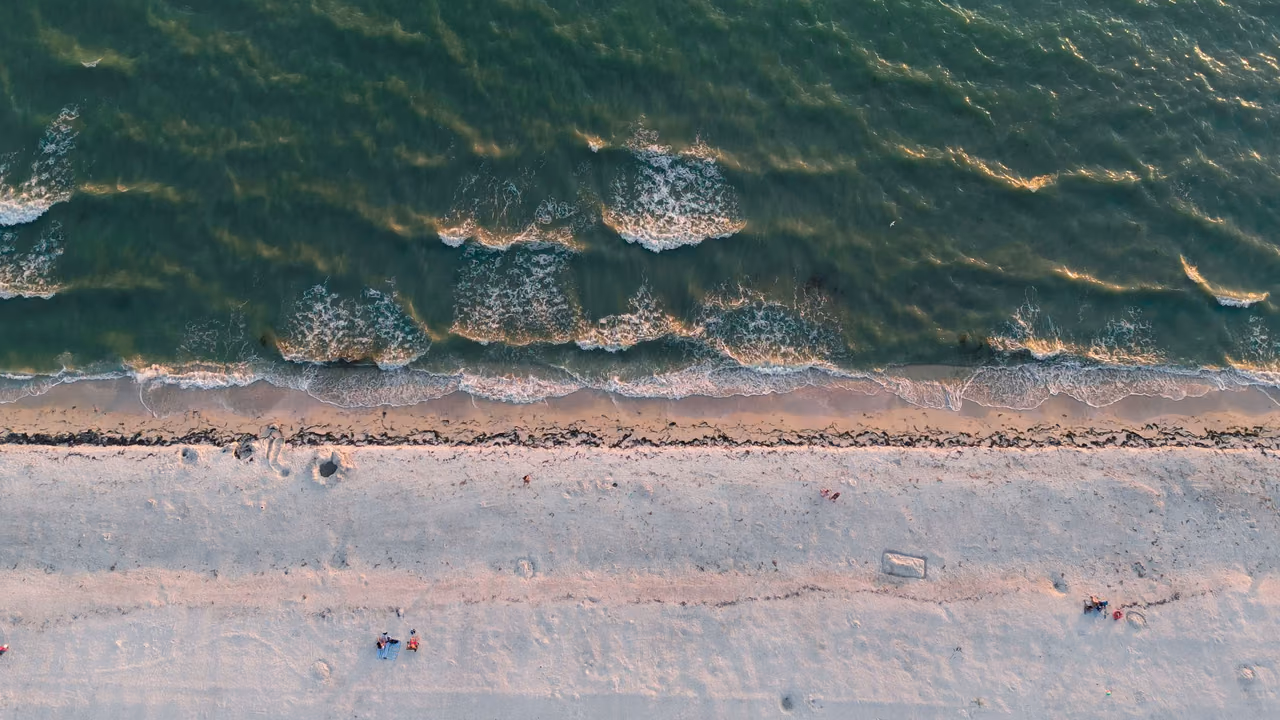 Aerial view of a Sarasota beach in Florida with sandy shores and gentle waves at sunset