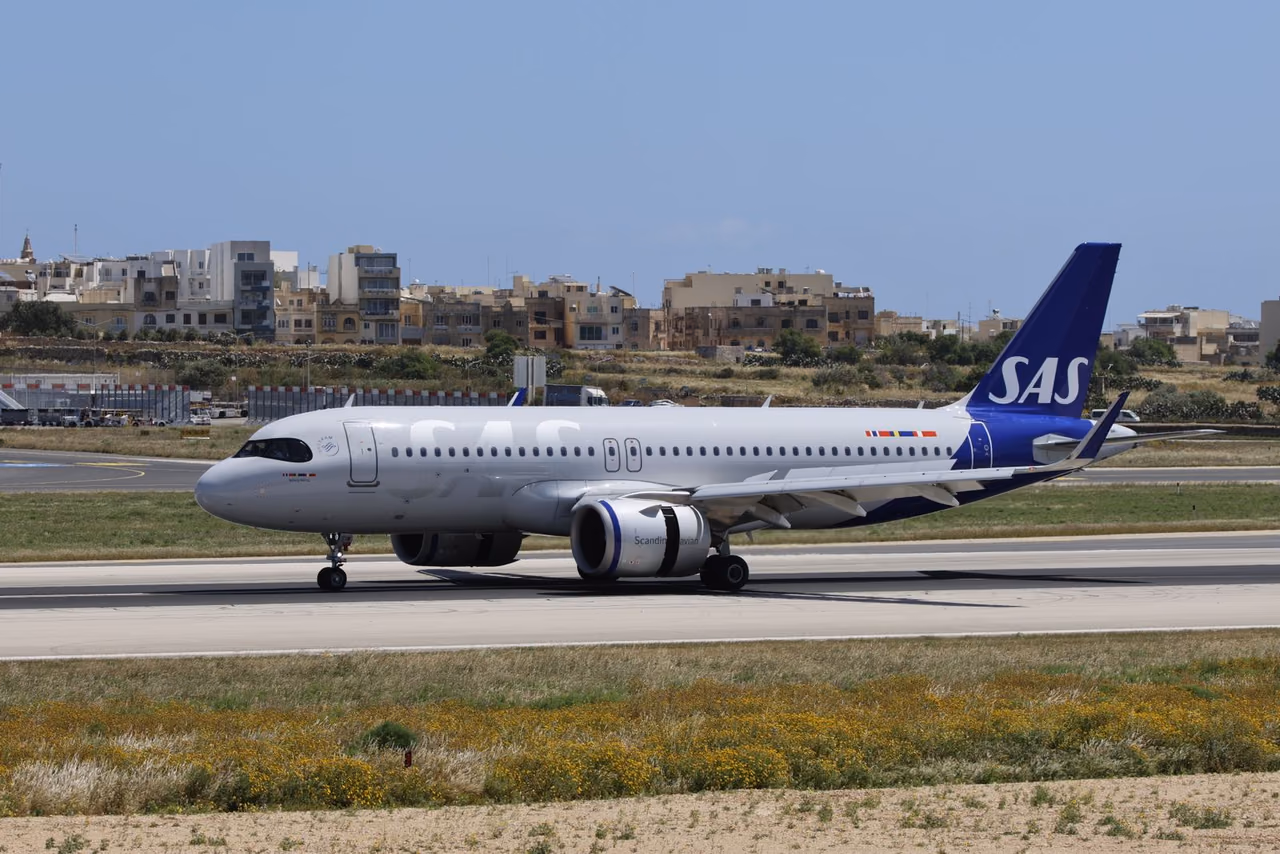 SAS Scandinavian Airlines jet on a runway in clear weather with airport buildings behind it