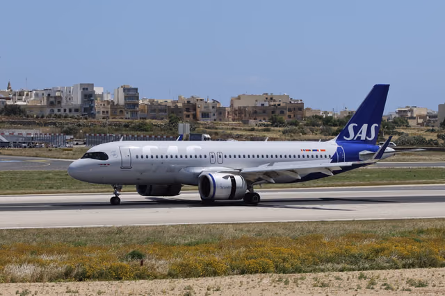 SAS Scandinavian Airlines jet on a runway in clear weather with airport buildings behind it