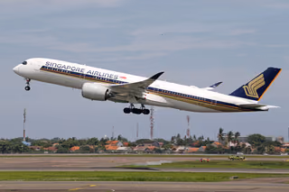 A Singapore Airlines Airbus A350 lifting off a runway with houses in the background