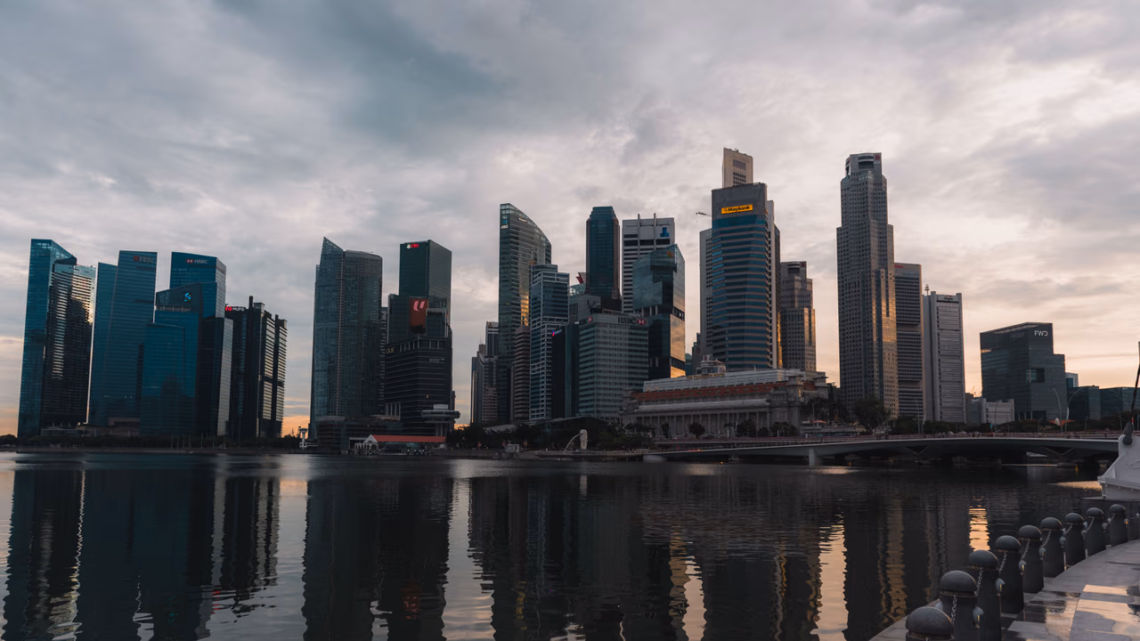 Singapore's downtown skyscrapers reflected in Marina Bay under a cloudy sky at dusk