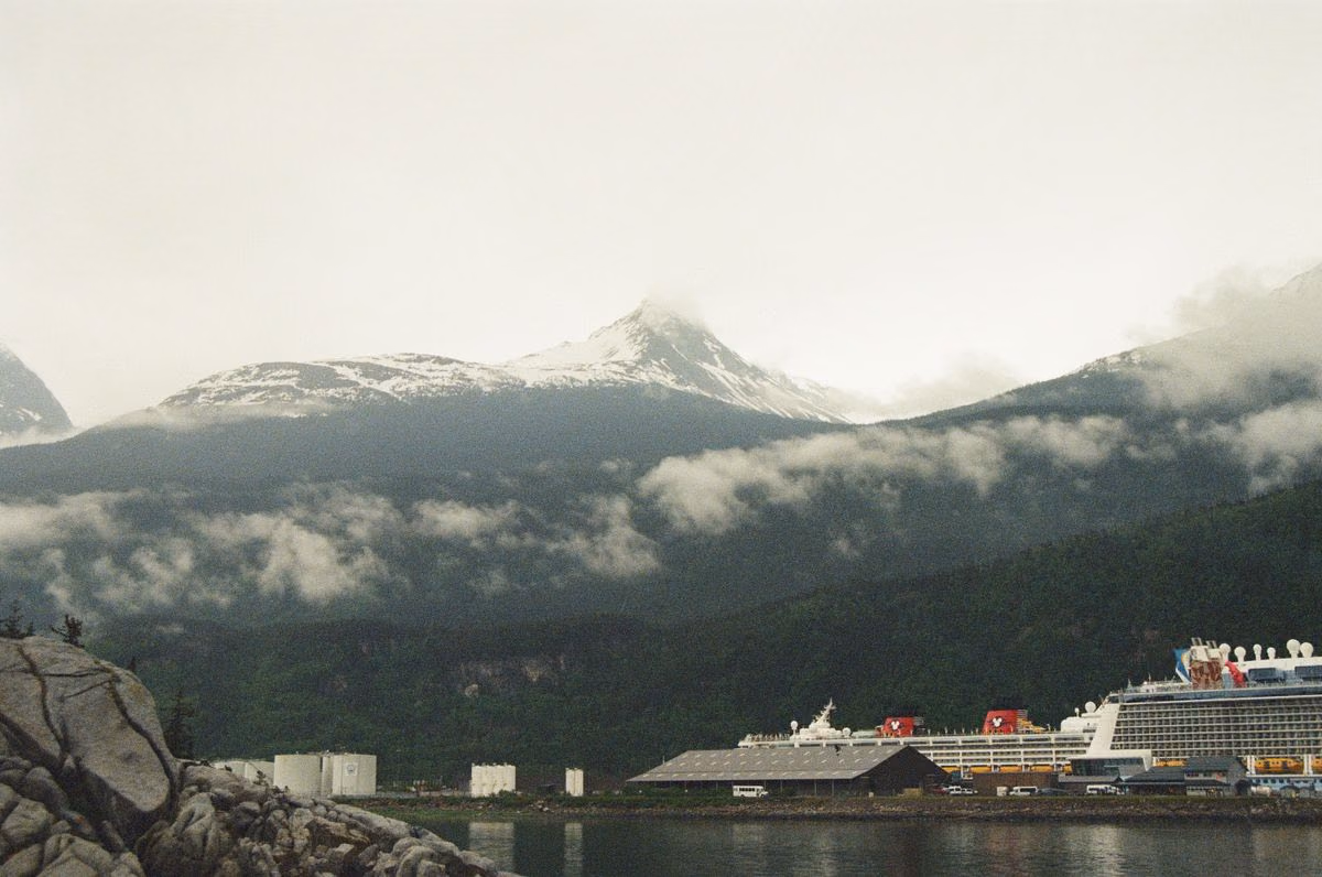 Cruise ship at the Skagway waterfront below fog-covered, snow-capped mountains