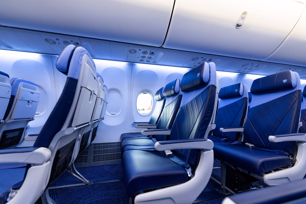 A row of navy Southwest Airlines seats beside a cabin window, with the seatbacks and tray tables of the row ahead in view