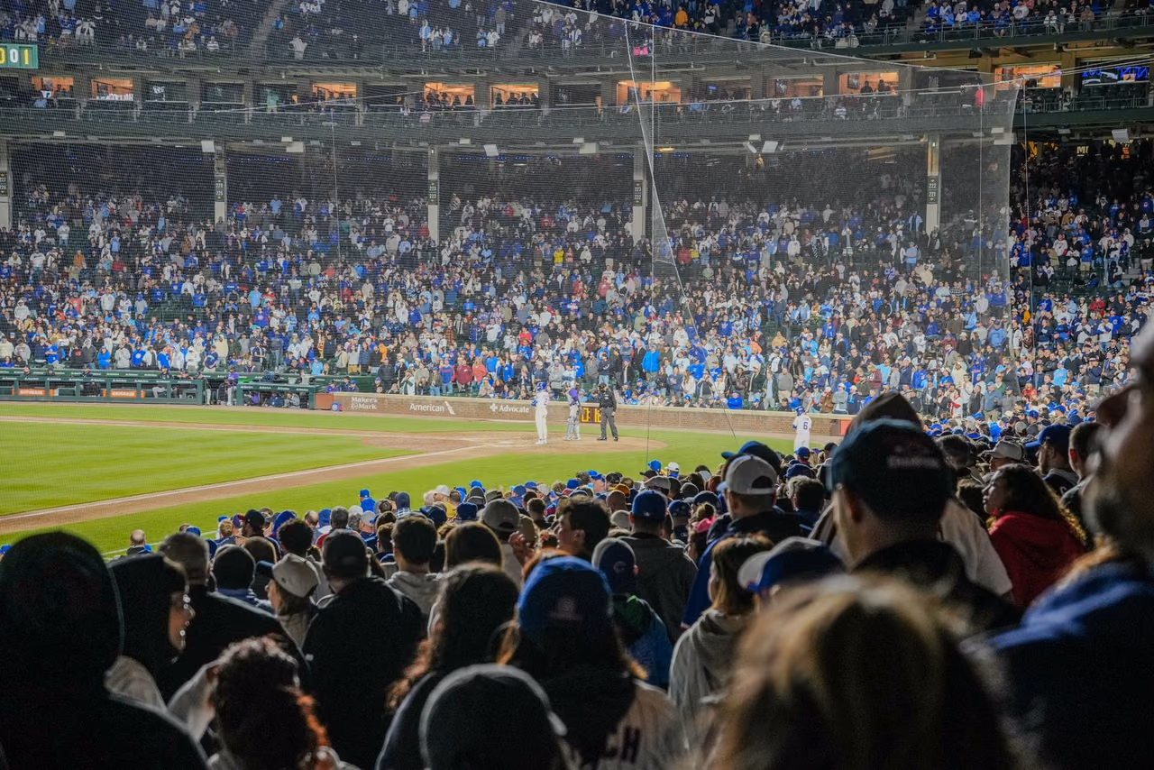A packed baseball stadium at night, with fans filling the stands under bright lights during a game