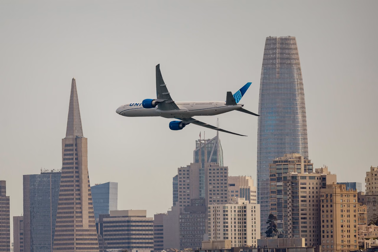 A United Airlines jet flying over the San Francisco skyline