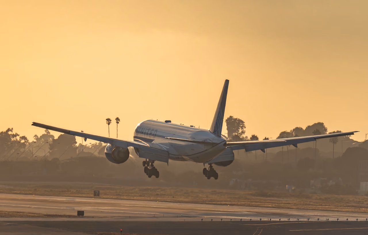 United Airlines jet landing on a runway at sunset