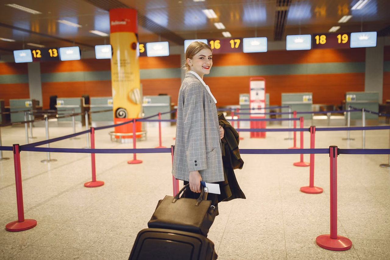 Traveler with a suitcase walking toward the check-in counters in an airport terminal