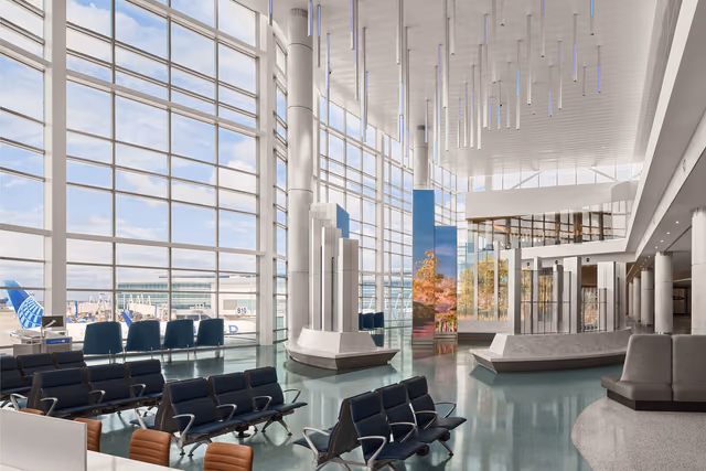 Glass-walled gate area in United's new Terminal B North Concourse at Houston, with seating rows and a tall digital art display