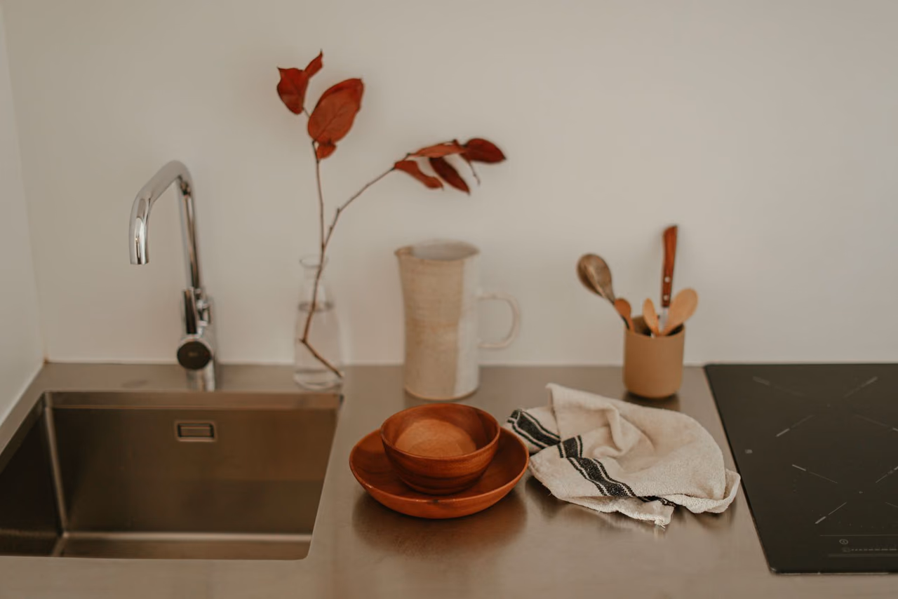 Modern kitchen with a stainless steel sink, a faucet and a minimalist counter with a few dishes beside it