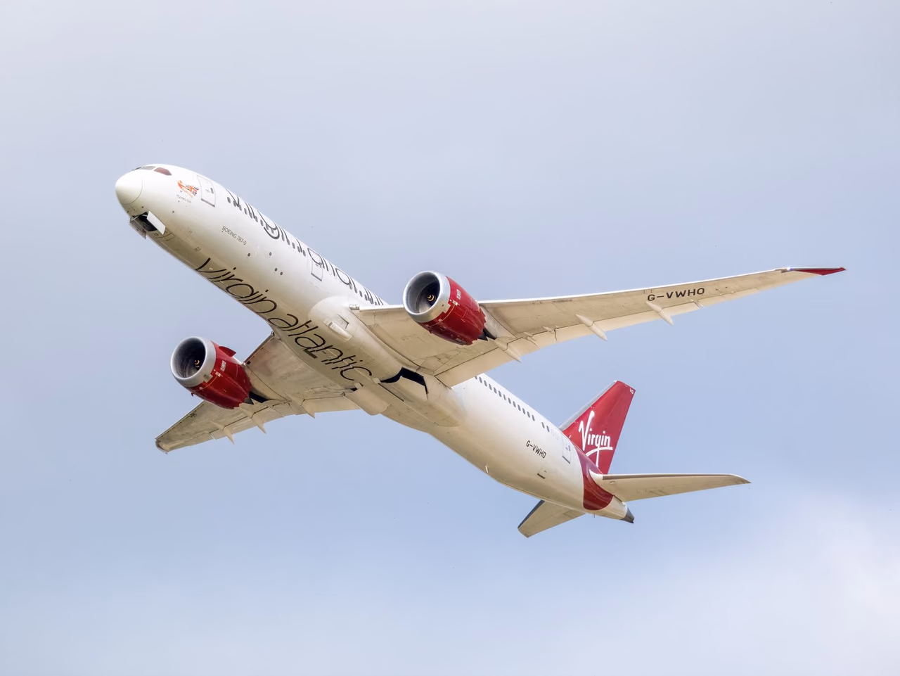 A Virgin Atlantic airliner banking upward after takeoff against a pale gray sky
