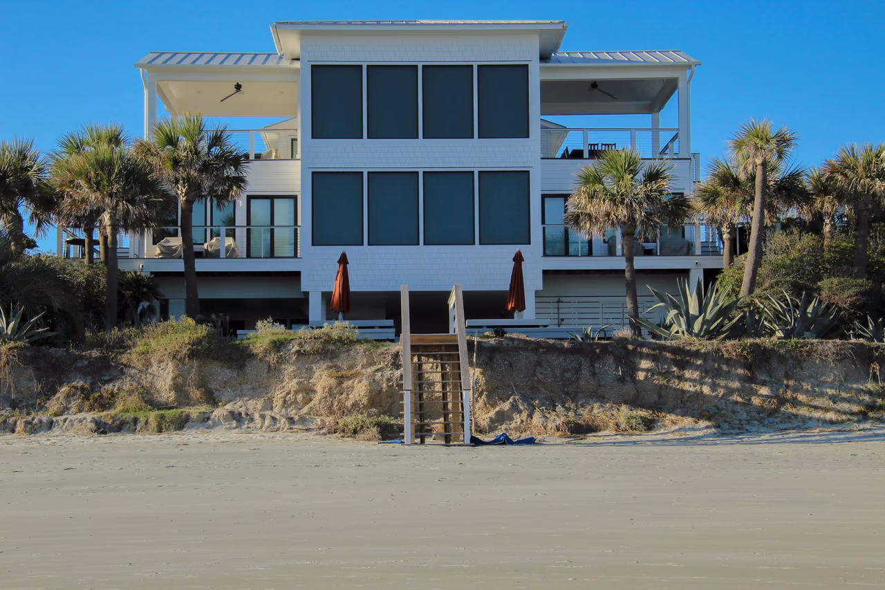 Modern beachfront house with palm trees under a clear blue sky